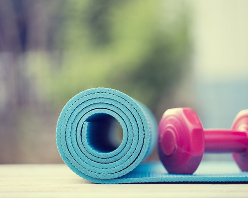 dumbbell and yoga mat on wood table